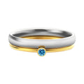 December birthstone ring in titanium steel with geometric engraving and gold accents on a grey background.