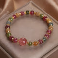Natural tourmaline and strawberry quartz 10mm round bead unisex bracelet on neutral background