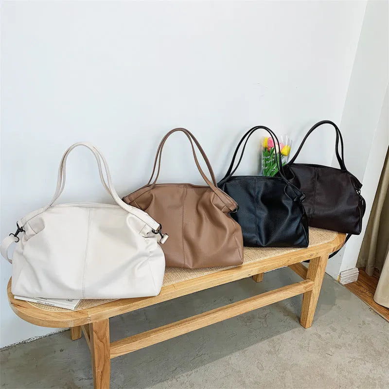 Large soft surface PU messenger bag in horizontal square shape with shoulder strap and top handle.