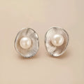 A pair of silver geometric stud earrings with white pearl details on a white background.