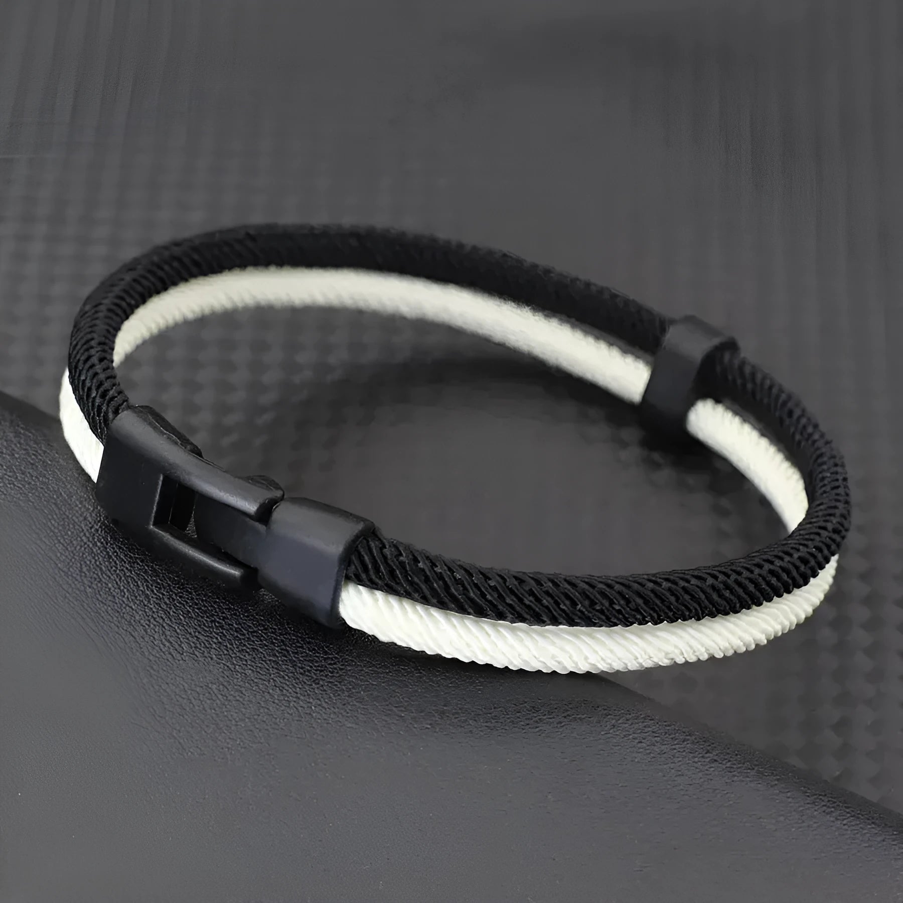 Handmade woven Milan rope hand strap in black and white, showing textured weave and attachment clip