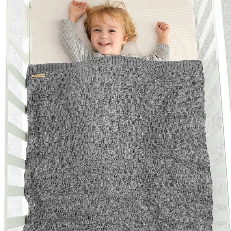 Solid colour acrylic baby blanket with textured lines, shown in a neutral shade, dimensions 70x90 cm